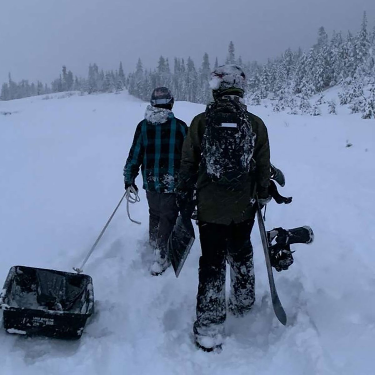 two guys walking carying snow shovels and their snowboards at mt hood oregon