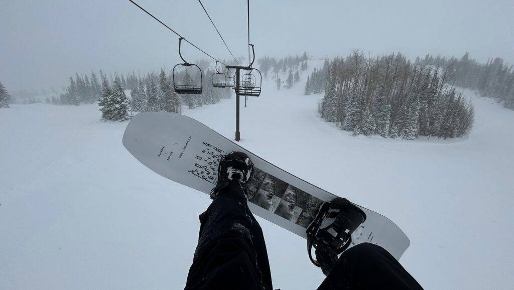 POV from a chairlift with a snowboard underfoot