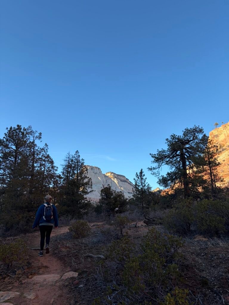 Hiking a dirt trail through ponderosa pines on the Triplets Trail at golden hour